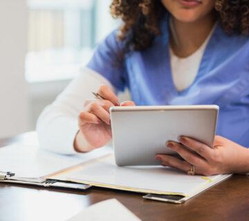 A home health caregiver views AI reports on a tablet.