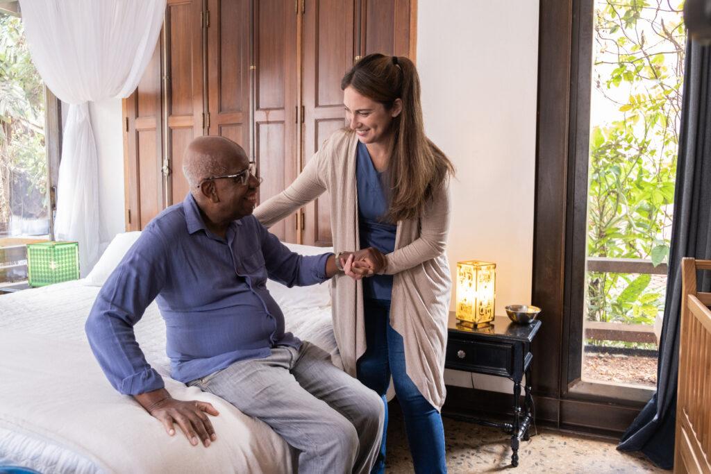 Elevate Home Care: The Power of Camera-Free, Wearable-Free RPM for Proactive Healthcare & Fall Prevention 1 Home caregiver helping a senior man standing up at home